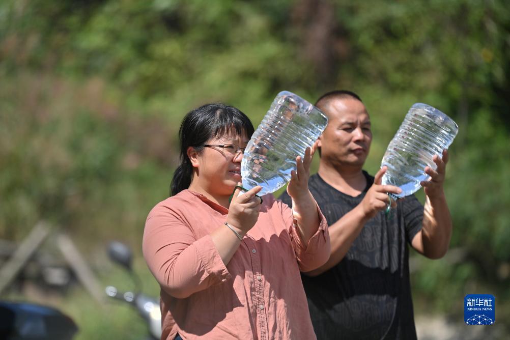 杨宁（左）在查看村民刚刚采集的水样，为山泉水引水工程做准备（10月8日摄）。新华社记者 黄孝邦 摄